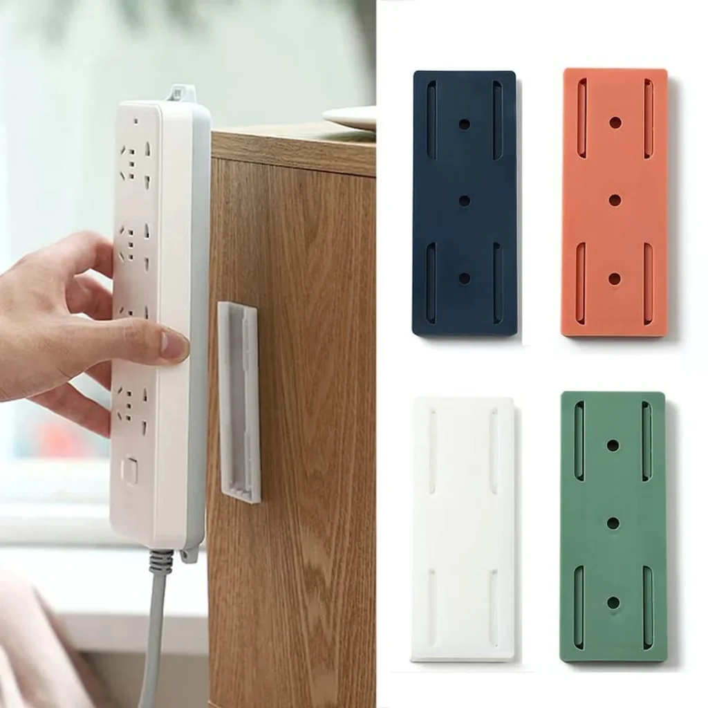 Wall-mounted self-adhesive power strip holder in four colors (white, navy, orange, green), demonstrating how it securely attaches to furniture for space-saving cable management.